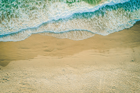 Aerial landscape of powerful ocean waves rolling into the sandy beach with copy spaceの写真素材