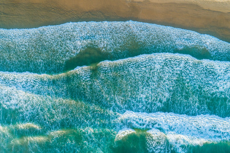 Looking down at ocean waves pound on the shore - aerial viewの写真素材