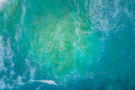 Two surfers rowing in opposite directions - aerial view with copy spaceの写真素材