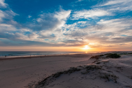 People walking on the beach at sunset in Australiaの写真素材