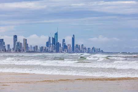 Ocean waves coming onto the shore with Gold Coast city skyscrapers in the backgroundの写真素材