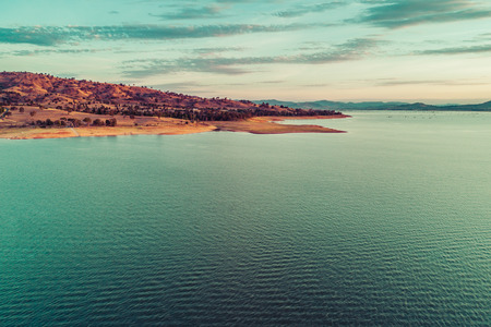 Yellow rolling hill and lake coastline at sunset - aerial viewの写真素材