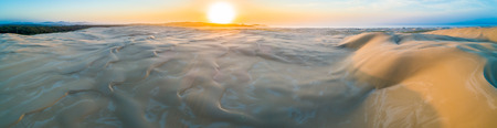 Wide aerial panorama of amazing sand dunes near ocean shore at sunriseの写真素材