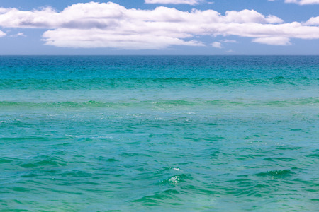 Calm turquoise ocean water under white fluffy cloudsの写真素材