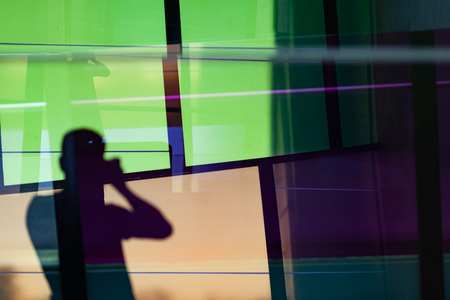 Blurred silhouette of photographer reflecting in colorful windows with copy space