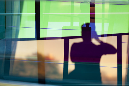 Blurred silhouette of person taking pictures reflecting in cloroed windows with many reflectionsの写真素材