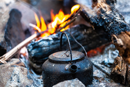 Campfire kettle closeup with blurred bonfire in the backgroundの写真素材