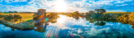 Sunset with sun flare over beautiful river in Australia - aerial panorama