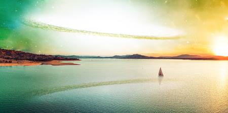 Scenic unreal sunset over beautiful lake and lonely sailboat on alien planet.の写真素材