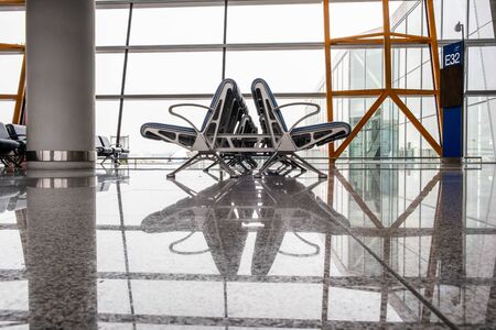 Empty seats reflecting in marble floor at airport terminalの写真素材