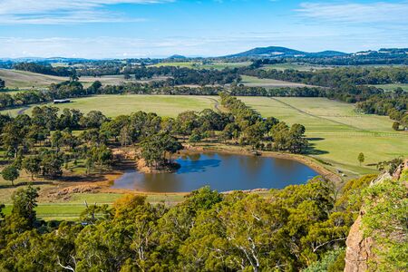 Small pond and native trees among meadows and pastures near Hanging Rock, Victoria, Australiaの写真素材