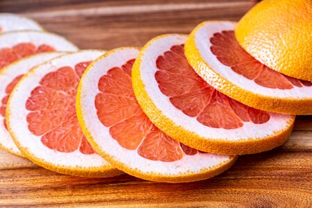 Red grapefruit slices on wooden cutting boardの写真素材