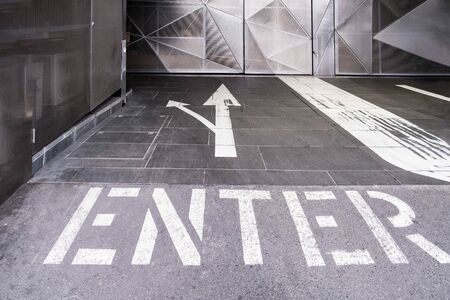 Enter text with two arrows painted on the floor of an underground parking entranceの写真素材