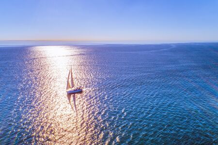 Lonely sailboat in wast waters backlit by the sun - aerial viewの写真素材