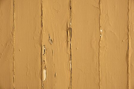 Mustard colored peeling paint on wooden planks backgroundの写真素材