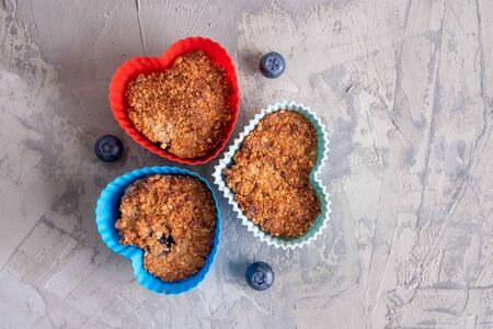 Homemade healthy cupcakes in heart shaped silicone moulds with blueberries  - top viewの写真素材