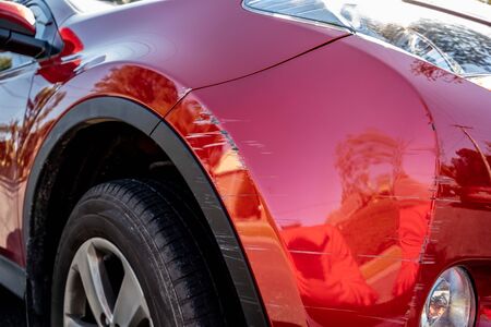 Deep scratches in red paint of car bumper