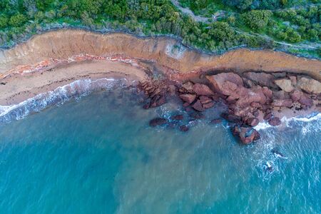 Looking down at large rocks and boulders on ocean beach - aerial viewの写真素材