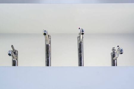 Four faucets displayed on white wallの写真素材