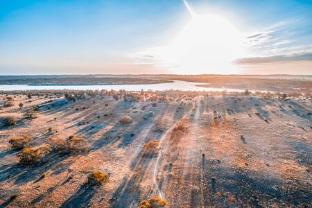 Bright sun shining over lake in Australian desert - aerial view