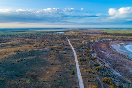 Gravel road passing through Australian desert at sunrise - aerial landscapeの写真素材