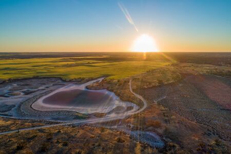 Sunset with sun flare over agricultural land and desert in Australiaの写真素材