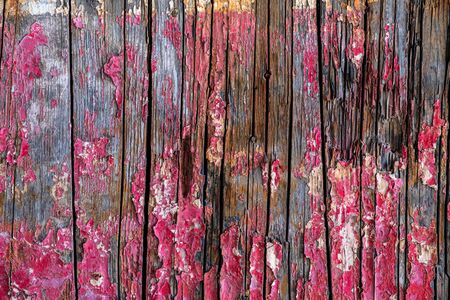 Old grungy wooden fence with peeling red paint backgroundの写真素材