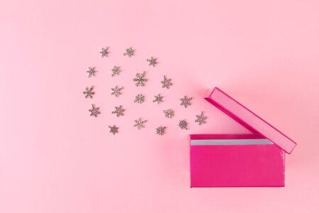 Cloud of snowflakes bursting out of open pink giftbox on pink background - top view with copy spaceの写真素材