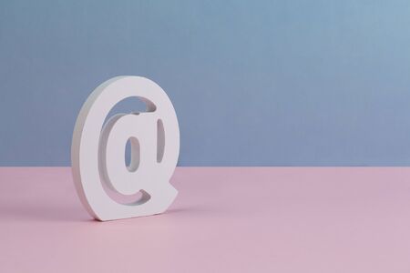 Carved Email symbol at placed on clean pink blue background with copy spaceの写真素材