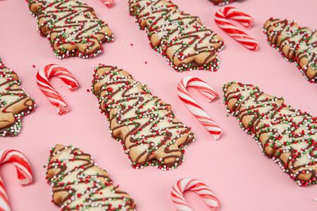 Christmas desserts - trees biscuits with candy canes on pink background with shallow focusの写真素材