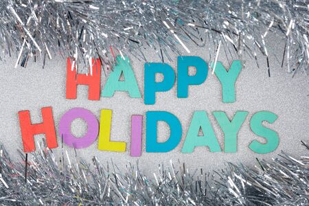 Happy Holidays text on glitter ornated with silver tinsel - top viewの写真素材