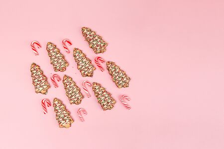 Christmas sweet food - trees biscuits with candy cantes on pink background. Top view with copy spaceの写真素材