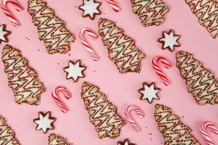 Christmas desserts background pattern - candy canes with stars and Christmas trees on pink, top viewの写真素材
