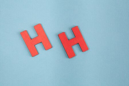 Capital letters H in red color arranged on blue background with copy spaceの写真素材