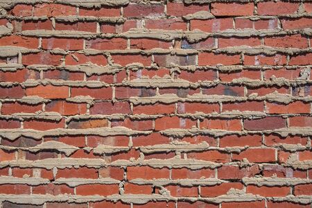 Retro red brick wall with cement filling oozing outの写真素材