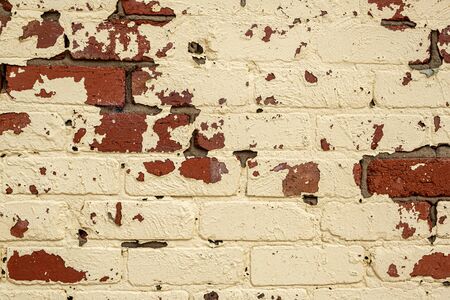 Beige paint peeling off retro brick wall background - closeupの写真素材