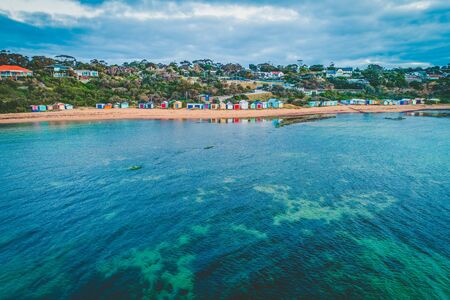 Shallow bay water reflecting colorful beach huts on ocean coastline in Australiaの写真素材