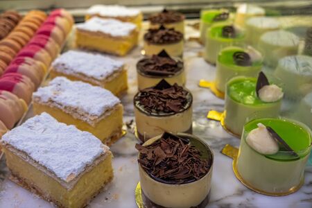 Rows of decorative sweet dessert at a cafe counter with shallow focusの写真素材