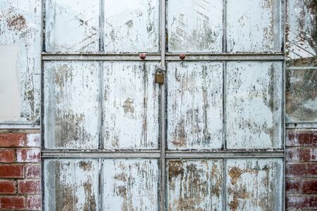 Locked glasshouse doors with peeling white paint closeupの写真素材