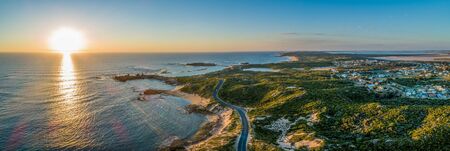 Scenic drive passing near ocean coastline and Beachport town at sunset - wide aerial panoramaの写真素材