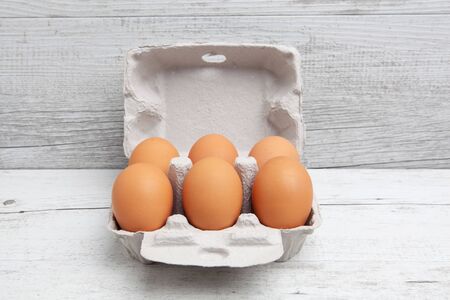 Six pack of eggs in carton on white wooden table with copy spaceの写真素材