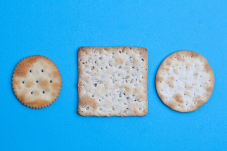 Round and square salted crackers on blue background - top view with copy spaceの写真素材