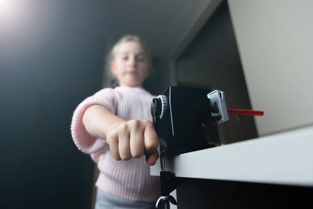 Girl sharpening a red pencil at home with shallow focusの写真素材