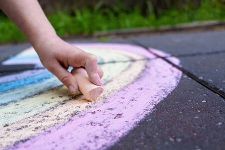 Closeup of child hand drawing rainbow using colorful chalkの写真素材