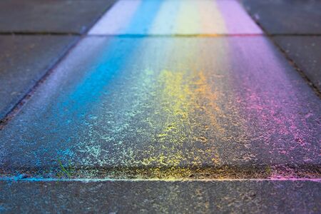 Perspective view of colorful rainbow drawing with chalk on pavement with shallow focus