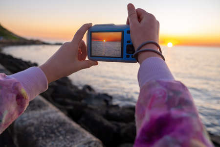 Child hands taking photo of sunset over seaの写真素材