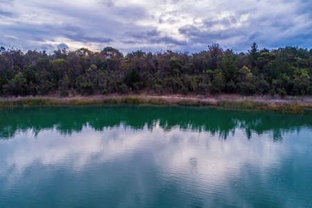Trees over water with reflections on cloudy day in australiaの写真素材