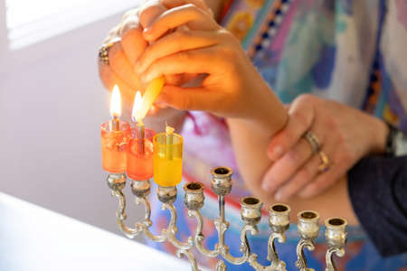 Woman hands helping a child to light Hanukkah candleの写真素材
