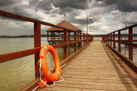 Lifebuoy on the pier on Lake Morzycko on an August summer dayのeditorial素材