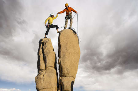 Team of climbers struggle to the summit of a challenging pinnacle.の写真素材
